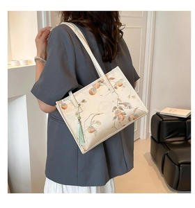 Detail of minimalist tote bag with orange persimmon print and green silk tassel charm