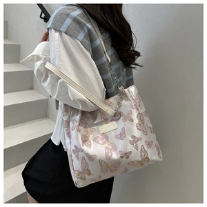 Detail of cream tote bag with purple butterfly print and silver chain strap