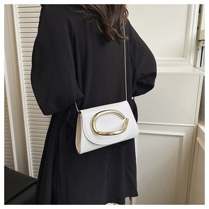 Detail of white PU leather crossbody bag with large gold oval buckle on a black dress