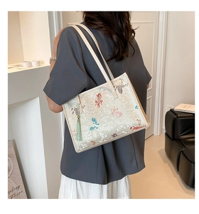 Detail of Chinese style tote bag featuring embroidered goldfish and green tassel accessory