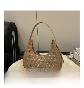 Detailed view of silver rivets on a khaki crescent-shaped handbag with leather handle