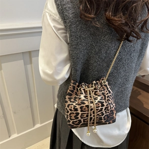 Chic leopard print bucket bag with gold chain strap and pearl drawstring detail on model