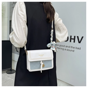 Detail of a chic cream crossbody bag with a blue flap and elegant silk scarf handle