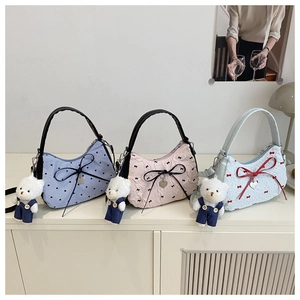 Détail de trois sacs à bandoulière pastel avec nœuds, cœurs et pendentifs ours en peluche
