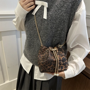 Detail of leopard print bucket bag with gold chain and faux pearl drawstring accents