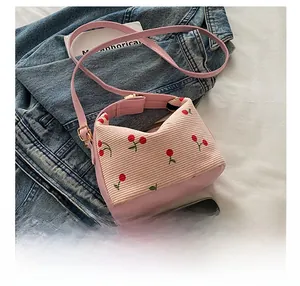 Detail of pink corduroy bucket bag with cherry embroidery and adjustable strap