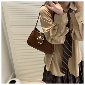 Close-up of retro brown shoulder bag featuring a prominent square gold metal buckle detail