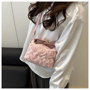 Détail de roses 3D sur sac à bandoulière rose porté par un mannequin en satin