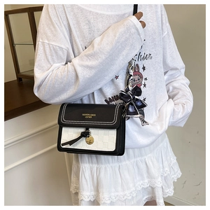 Detail of woven texture small square bag with contrast bow and metal stud embellishments