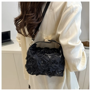 Détail du sac à main à fleurs 3D noires avec boucle dorée et bandoulière en cuir