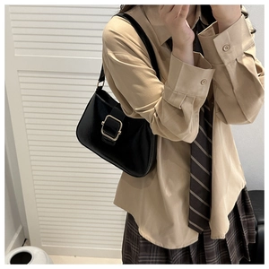 Classic black leather underarm bag with gold metal buckle shown on model in JK style