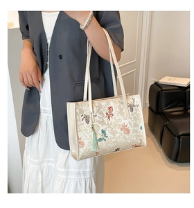 Detail of Chinese style embroidery featuring goldfish and clouds on a white tote bag