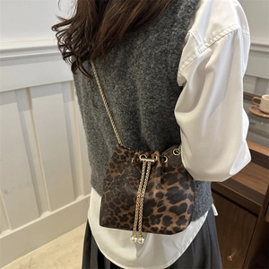Detail of leopard print bucket bag with gold chain strap and elegant pearl drawstring