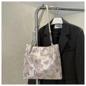 Close-up of pearl white fabric tote with pink butterfly jacquard and silver chain strap