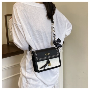 Detail of crossbody bag featuring checkerboard pattern and silk scarf handle accent