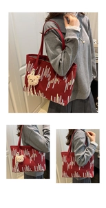 Detailed close-up of large red tote bag with wavy embroidery and plush bear charm