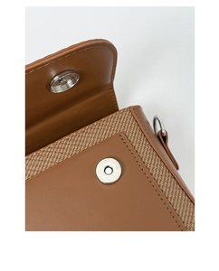 Detailed macro view of silver magnetic clasp and contrast stitching on a leather handbag
