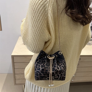 Detailed view of leopard print bucket bag with gold chain strap and pearl drawstring