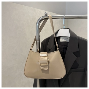 Detail of cream leather shoulder bag with a gold square buckle on a grey background