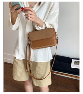 Brown leather and woven vintage crossbody bag shown on a model in a cozy indoor setting