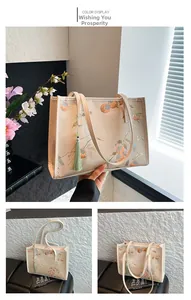 Detail of beige tote bag with embroidered persimmon pattern and green tassel charm