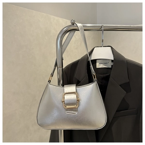 Detail of silver metallic underarm bag featuring a gold square buckle and smooth PU leather