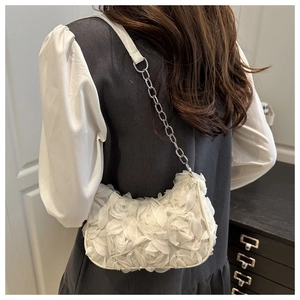 Close-up of white shoulder bag with 3D floral petals and silver metal chain strap