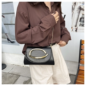Close-up of black leather crossbody bag featuring a golden C logo and chain strap