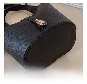 Close-up of black litchi pattern leather bucket bag with precise stitching and gold lock