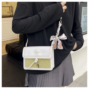 Detail of a square crossbody bag featuring olive green checkerboard and silk scarf strap