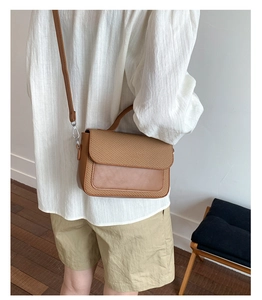 Close-up of brown leather and woven texture crossbody bag shown from the side on a model