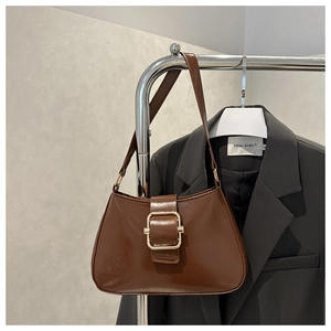 Detail of vintage brown leather underarm bag with large gold buckle on grey blazer