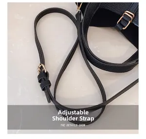 Detail view of adjustable strap with gold buckle on black lychee pattern leather bag