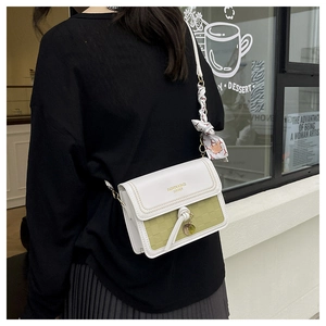 Detail of color-block crossbody bag with woven texture and floral scarf accessory