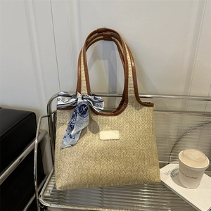 Large woven straw tote bag with brown leather handles and decorative floral silk scarf