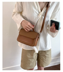 Detailed close-up showing the brown woven leather texture and elegant shoulder bag design