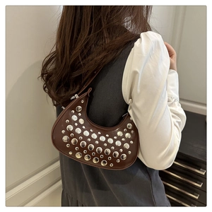 Close-up of a dark brown crescent bag featuring metallic silver studs and leather texture