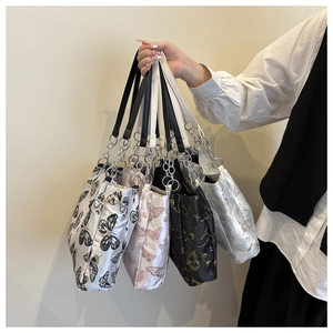 Detail of satin tote bags with butterfly prints and elegant metal chain straps