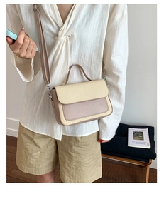 Detail of contrast stitching crossbody bag with beige woven lid and adjustable strap