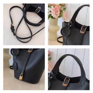 Detail of black lychee leather bucket bag with gold hardware and smiley charm