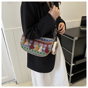 Détail d'un sac bandoulière tissé ethnique avec de longs pompons colorés et un mini-sac