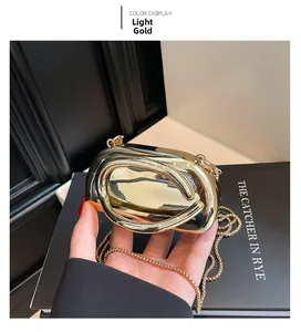 Detailed close-up of a light gold hard shell metal evening clutch with mirror finish and chain