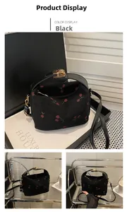 Detail of black corduroy cherry print bag with golden clasp and leather strap