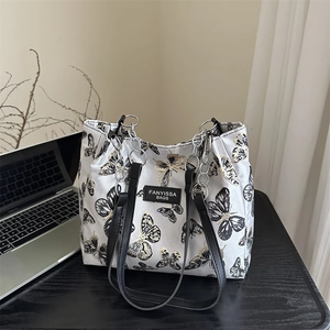 Minimalist cream tote bag with black butterfly embroidery and leather chain straps