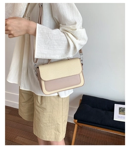 Detail of color-block crossbody bag with beige woven texture and soft pink leather accents