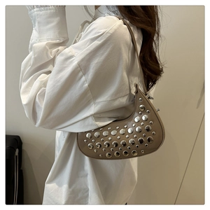 Side view of khaki crescent shoulder bag with silver studs worn by a model