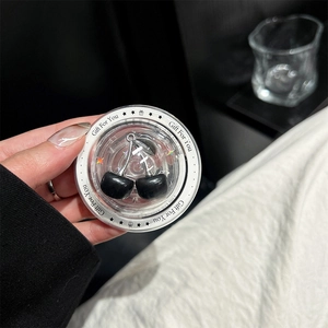 Detail view of a black cherry phone charm inside a Gift For You transparent round box