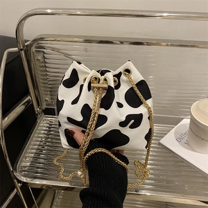 Fashionable cow print drawstring bucket bag with gold chain and pearl details