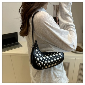 Detail of black crescent shoulder bag with silver metallic rivets in Y2K style