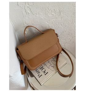 Close-up of contrast color handbag with straw weave detail and smooth brown faux leather